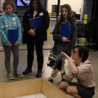 3 k-12 students looking at a project